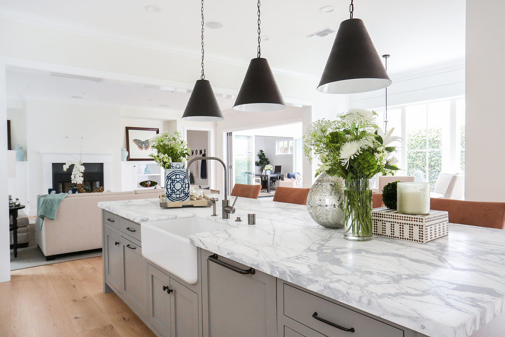 Design ideas for a country open plan kitchen in Orange County with a farmhouse sink, marble benchtops, white splashback, stainless steel appliances, light hardwood floors and with island.