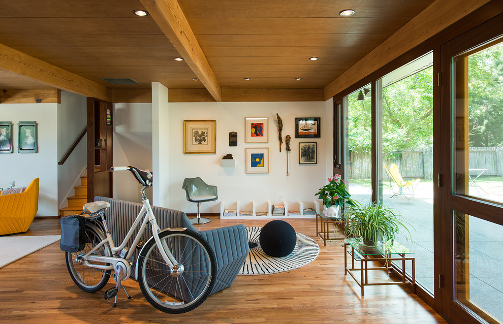 This is an example of a midcentury open concept living room in Denver with white walls and light hardwood floors.