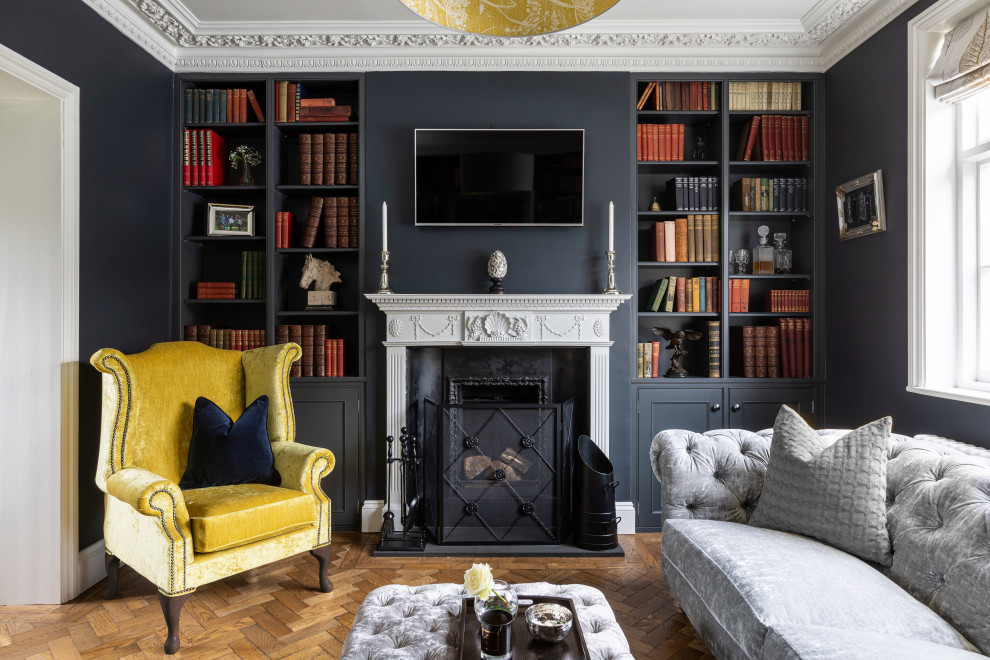 Inspiration for a mid-sized traditional formal enclosed living room in Essex with blue walls, medium hardwood floors, a wood stove, a plaster fireplace surround, a wall-mounted tv and brown floor.