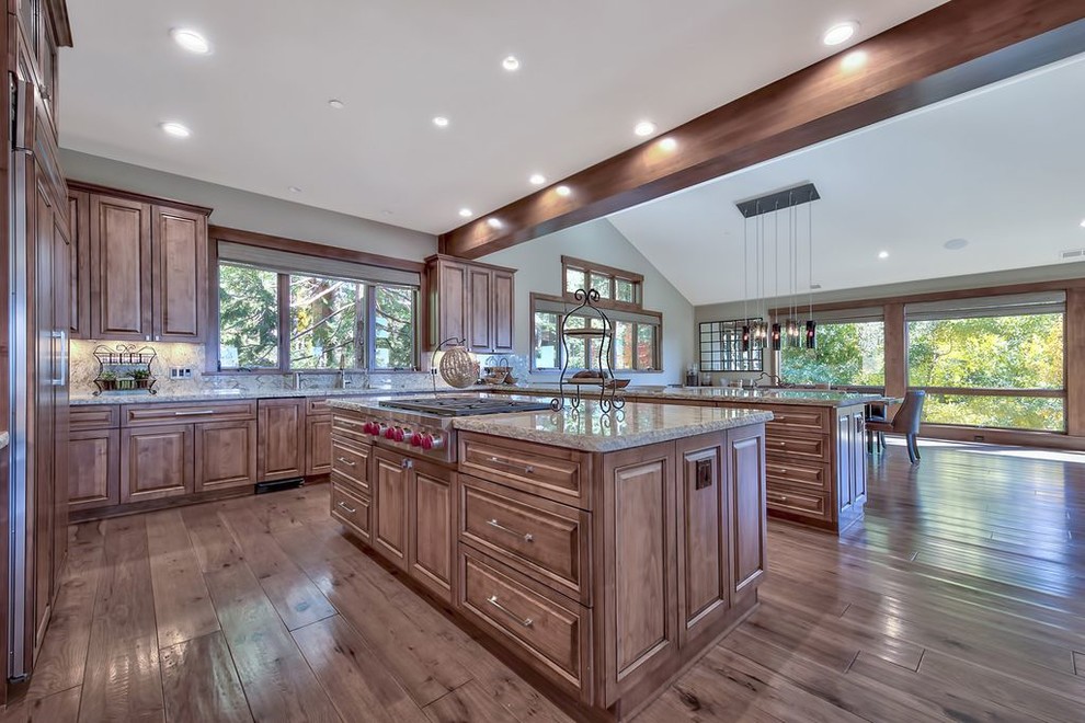 Huge transitional u-shaped medium tone wood floor and multicolored floor open concept kitchen photo with a double-bowl sink, raised-panel cabinets, medium tone wood cabinets, granite countertops, multicolored backsplash, stone slab backsplash, paneled appliances, an island and multicolored countertops
