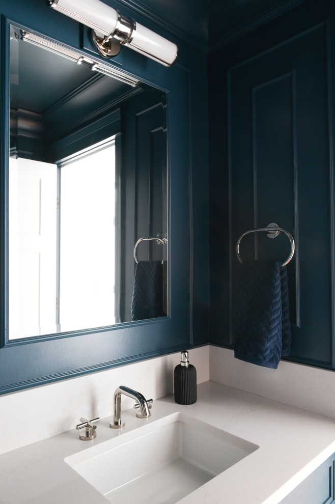 Design ideas for a small traditional powder room in Vancouver with shaker cabinets, blue cabinets, a two-piece toilet, blue walls, medium hardwood floors, an undermount sink, engineered quartz benchtops, white benchtops, a freestanding vanity and panelled walls.