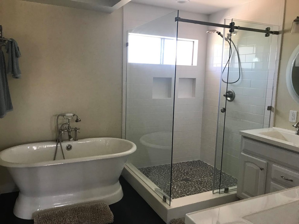 Design ideas for a large transitional master bathroom in Orange County with raised-panel cabinets, white cabinets, a freestanding tub, a corner shower, white tile, ceramic tile, beige walls, dark hardwood floors, an integrated sink, glass benchtops, brown floor, a sliding shower screen and white benchtops.