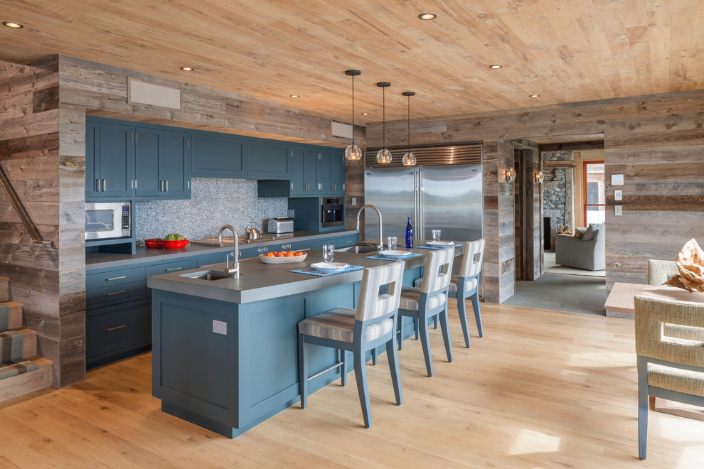 Inspiration for a mid-sized country single-wall eat-in kitchen in Boston with an undermount sink, shaker cabinets, blue cabinets, multi-coloured splashback, mosaic tile splashback, stainless steel appliances, light hardwood floors, with island, brown floor and grey benchtop.