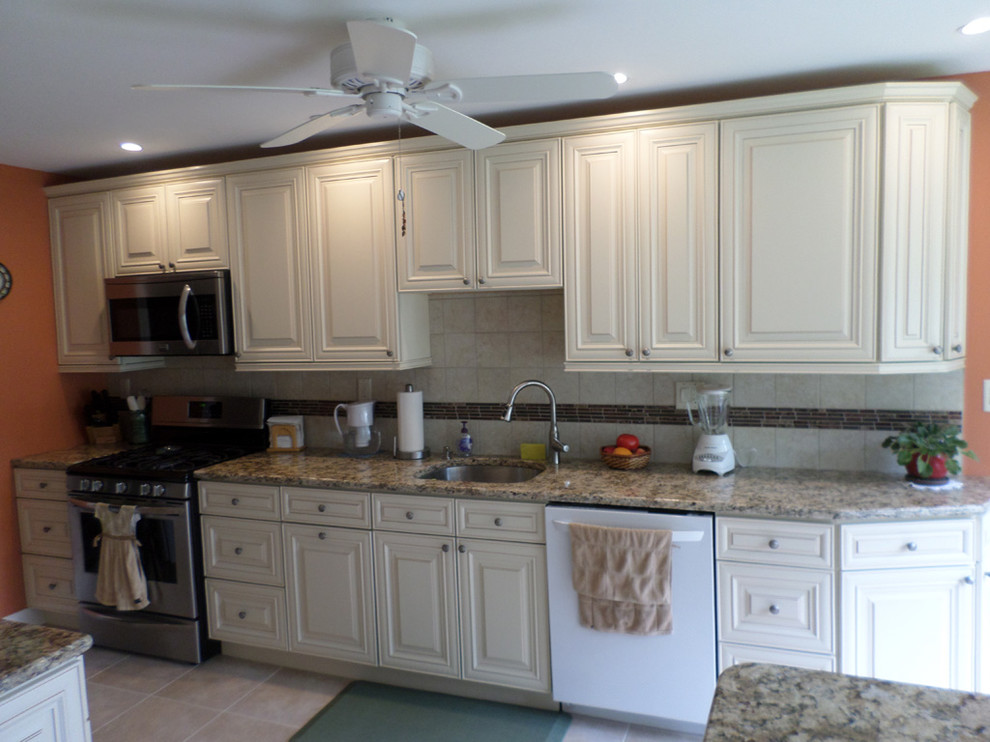 Photo of a mid-sized midcentury galley separate kitchen in Philadelphia with raised-panel cabinets, white cabinets, granite benchtops, beige splashback, stone tile splashback, white appliances and a peninsula.