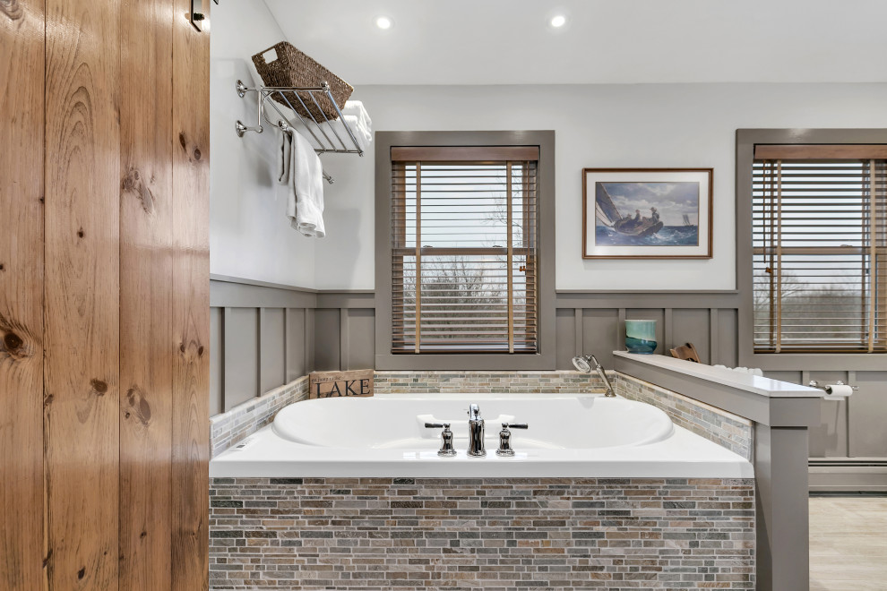 Amerikansk inredning av ett mellanstort en-suite badrum, med ett platsbyggt badkar, en dubbeldusch, en toalettstol med separat cisternkåpa, vit kakel, cementkakel, grå väggar, ett avlångt handfat, beiget golv och dusch med gångjärnsdörr