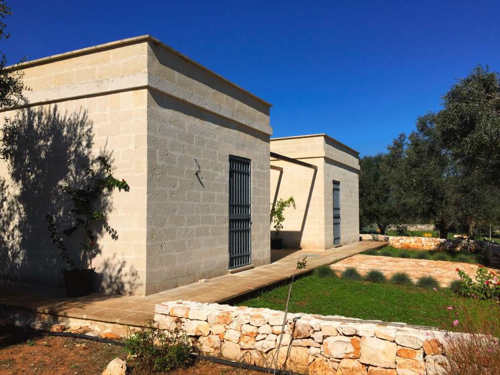 Inspiration for a mediterranean one-storey house exterior in Bari with stone veneer and a flat roof.