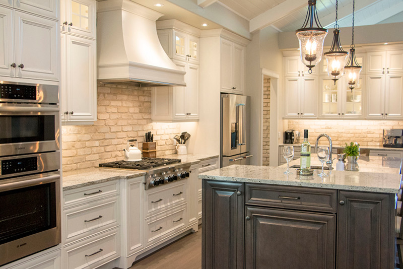 Large transitional l-shaped eat-in kitchen photo with a double-bowl sink, shaker cabinets, white cabinets, beige backsplash, stainless steel appliances and an island