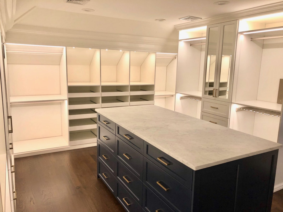 This is an example of a large traditional gender-neutral walk-in wardrobe in New York with recessed-panel cabinets, blue cabinets and dark hardwood floors.