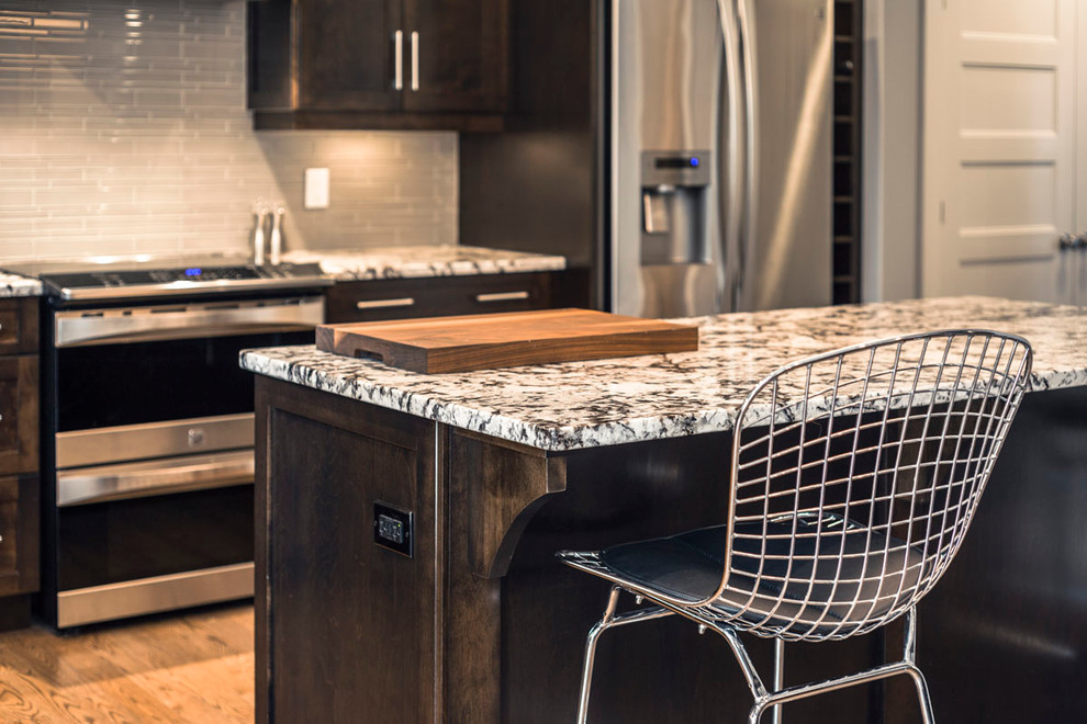 Eat-in kitchen - mid-sized transitional l-shaped dark wood floor eat-in kitchen idea with an undermount sink, shaker cabinets, dark wood cabinets, granite countertops, gray backsplash, glass tile backsplash, stainless steel appliances and an island