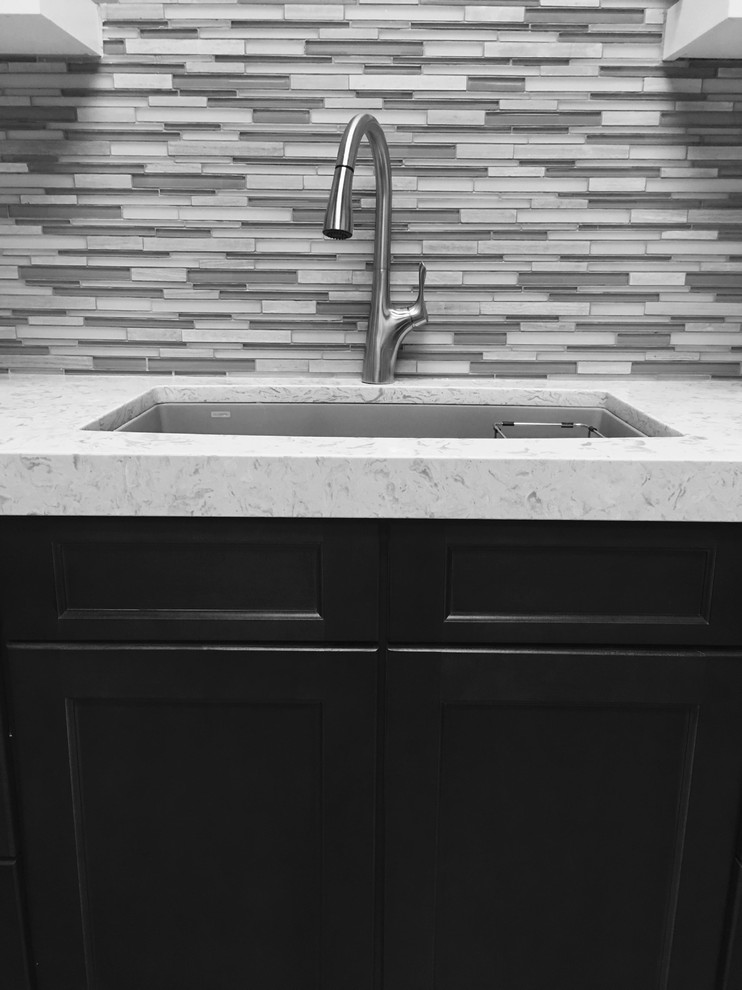 Example of a mid-sized transitional l-shaped porcelain tile enclosed kitchen design in Austin with a double-bowl sink, recessed-panel cabinets, dark wood cabinets, quartz countertops, beige backsplash, glass tile backsplash, stainless steel appliances and no island