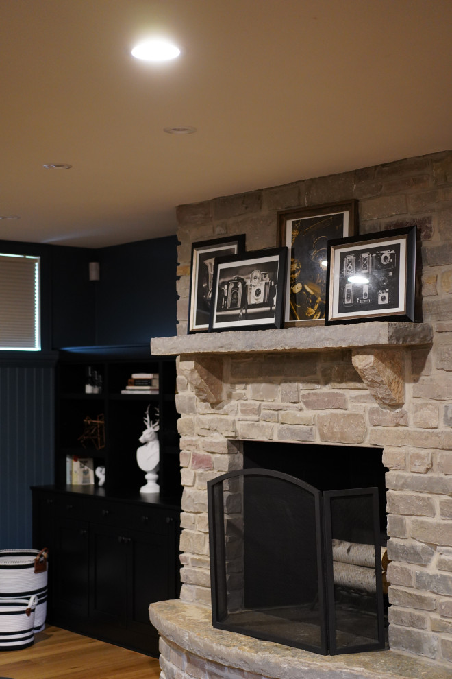 Foto de sótano en el subsuelo clásico renovado grande con bar en casa, paredes azules, suelo de madera clara, todas las chimeneas y marco de chimenea de piedra