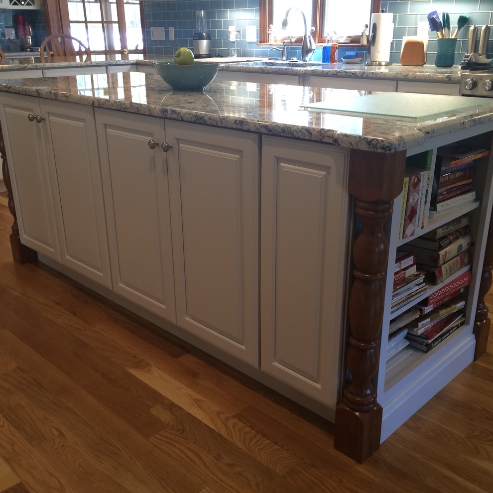 Example of a transitional u-shaped medium tone wood floor eat-in kitchen design in Boston with an undermount sink, raised-panel cabinets, white cabinets, granite countertops, blue backsplash, glass tile backsplash, stainless steel appliances and an island