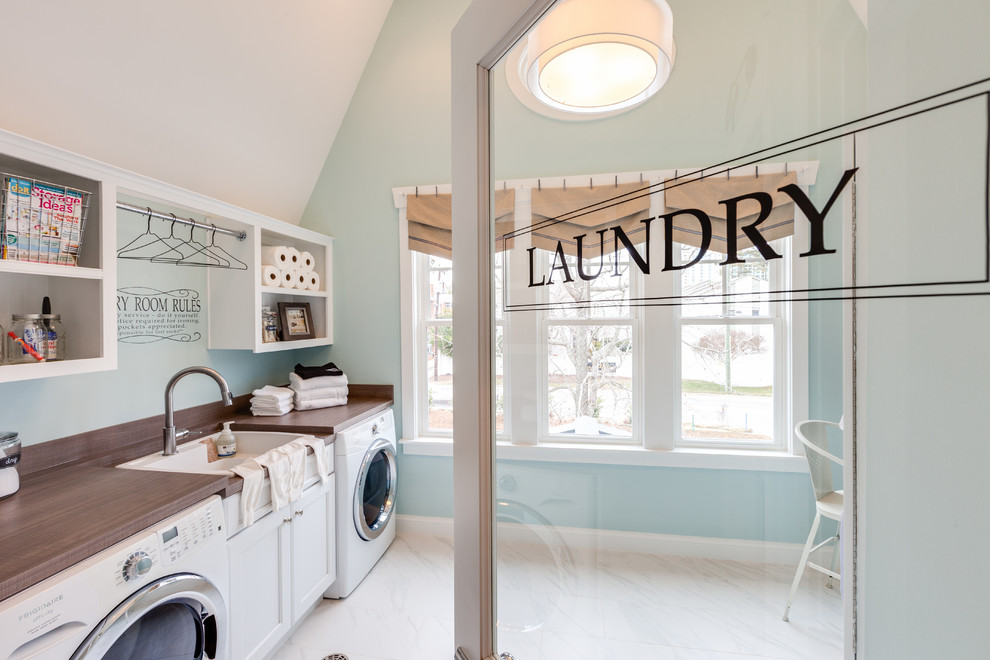 Design ideas for a large beach style galley utility room in Other with a drop-in sink, recessed-panel cabinets, white cabinets, laminate benchtops, blue walls, marble floors and a side-by-side washer and dryer.
