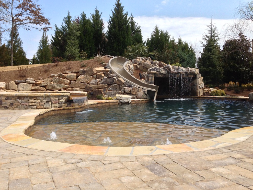 Inspiration for a large arts and crafts backyard custom-shaped natural pool in Atlanta with a water slide and concrete pavers.