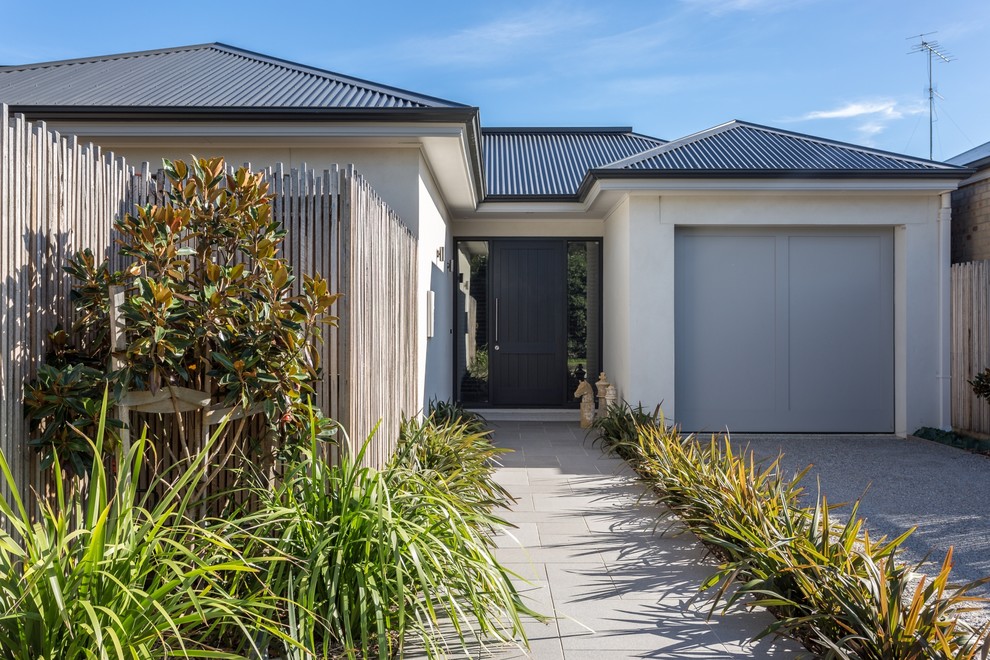 Inspiration for a mid-sized beach style entry hall in Geelong with beige walls, concrete floors, a single front door, a black front door and grey floor.
