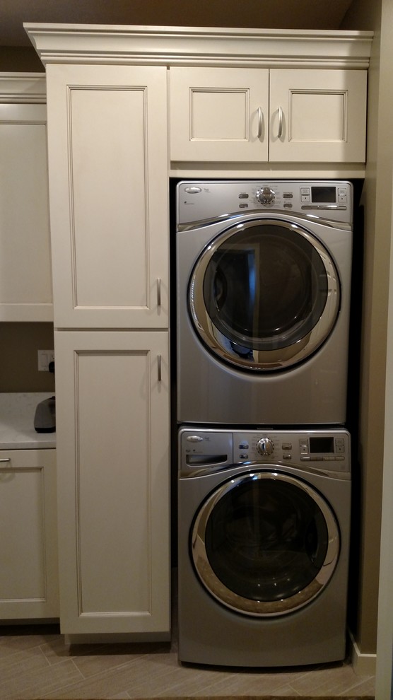Photo of a transitional laundry room in Other with an undermount sink, beige cabinets, grey walls, ceramic floors, a stacked washer and dryer, recessed-panel cabinets and quartz benchtops.