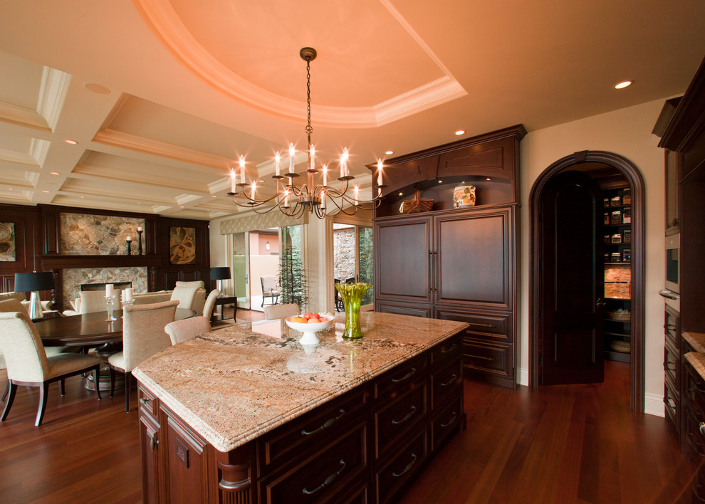 Inspiration for a huge rustic single-wall porcelain tile and brown floor open concept kitchen remodel with an undermount sink, dark wood cabinets, granite countertops, porcelain backsplash, beaded inset cabinets, beige backsplash, paneled appliances and an island