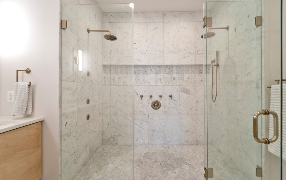 Свежая идея для дизайна: большая главная ванная комната в стиле модернизм с плоскими фасадами, светлыми деревянными фасадами, двойным душем, раздельным унитазом, белой плиткой, мраморной плиткой, белыми стенами, мраморным полом, врезной раковиной, столешницей из искусственного кварца, белым полом, душем с распашными дверями, белой столешницей, нишей, тумбой под две раковины и подвесной тумбой - отличное фото интерьера