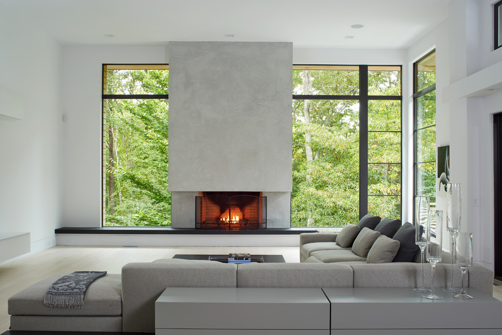 Inspiration for a large modern formal open concept living room in Boston with white walls, light hardwood floors, a standard fireplace, a concrete fireplace surround, no tv and beige floor.