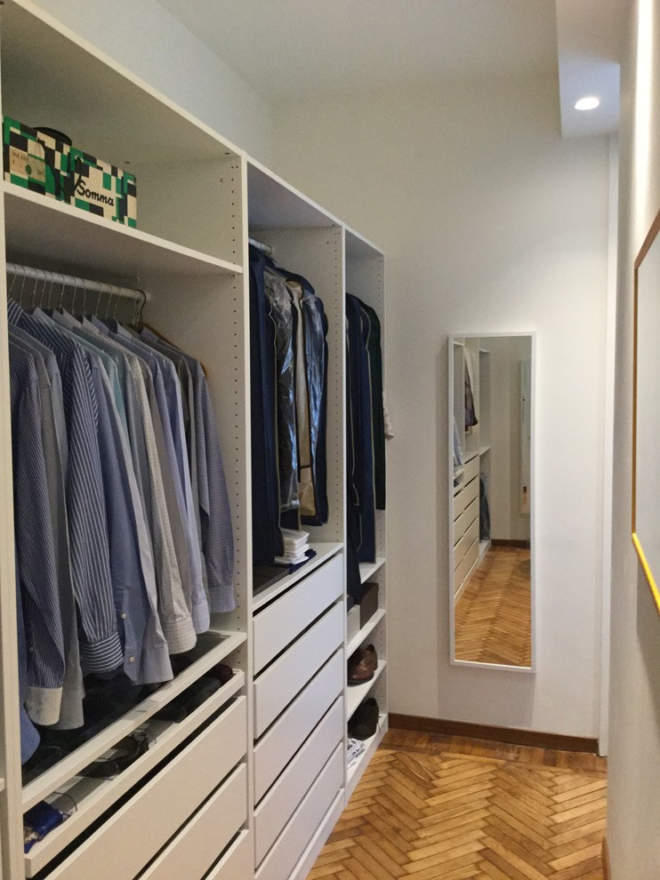 Inspiration for a small modern men's walk-in wardrobe in Milan with open cabinets, white cabinets and light hardwood floors.