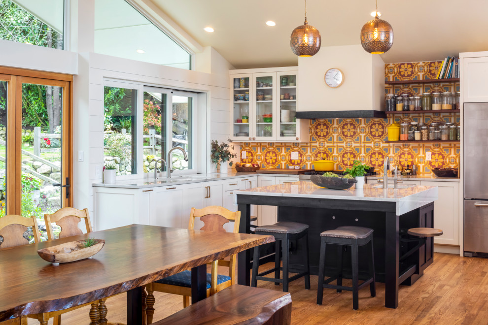 Mid-sized mediterranean l-shaped open plan kitchen in Seattle with shaker cabinets, white cabinets, quartzite benchtops, with island, an undermount sink, multi-coloured splashback, cement tile splashback, stainless steel appliances, medium hardwood floors, white benchtop and vaulted.