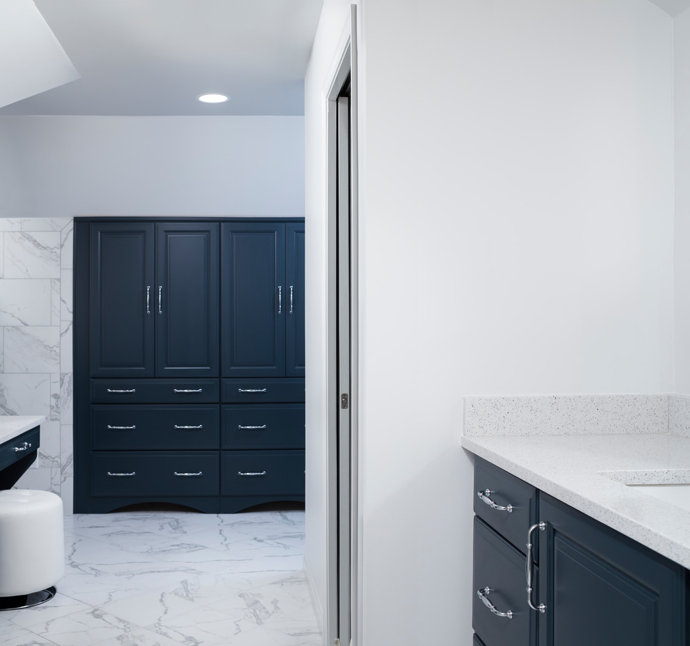 This is an example of a large modern master bathroom in Birmingham with raised-panel cabinets, blue cabinets, a hot tub, a curbless shower, a one-piece toilet, white tile, ceramic tile, white walls, ceramic floors, a drop-in sink, quartzite benchtops, white floor and a hinged shower door.