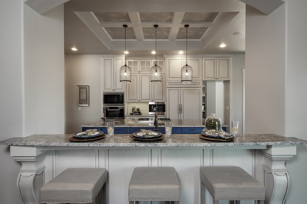 Inspiration for a large transitional dark wood floor kitchen remodel in Boise with an undermount sink, raised-panel cabinets, gray cabinets, granite countertops, white backsplash, ceramic backsplash, paneled appliances and two islands