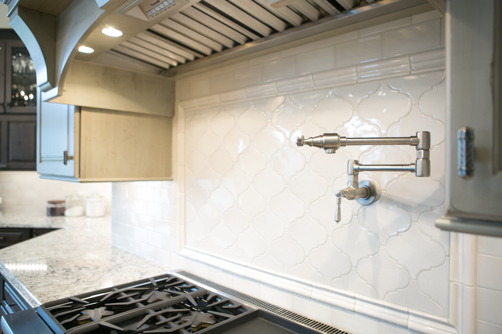 Large transitional u-shaped medium tone wood floor and brown floor kitchen photo in Indianapolis with a farmhouse sink, raised-panel cabinets, dark wood cabinets, granite countertops, white backsplash, subway tile backsplash, paneled appliances, an island and multicolored countertops