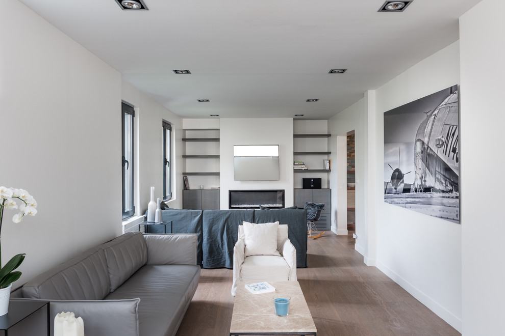 Exemple d'un salon tendance de taille moyenne et ouvert avec une bibliothèque ou un coin lecture, un mur multicolore, un sol en bois brun, aucune cheminée, un téléviseur fixé au mur et un sol marron.