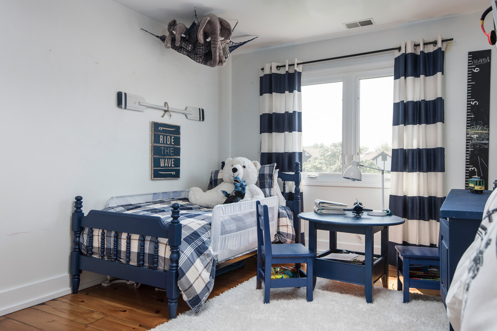 Photo of a beach style kids' bedroom for kids 4-10 years old and boys in Chicago with white walls, dark hardwood floors and brown floor.