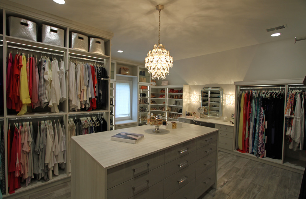 Inspiration for a large transitional women's walk-in wardrobe in Detroit with glass-front cabinets, light wood cabinets, light hardwood floors and grey floor.