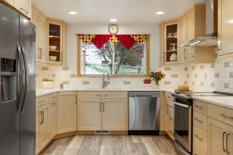 Example of a transitional galley eat-in kitchen design with an undermount sink, shaker cabinets, light wood cabinets, quartzite countertops, beige backsplash, subway tile backsplash, stainless steel appliances and white countertops