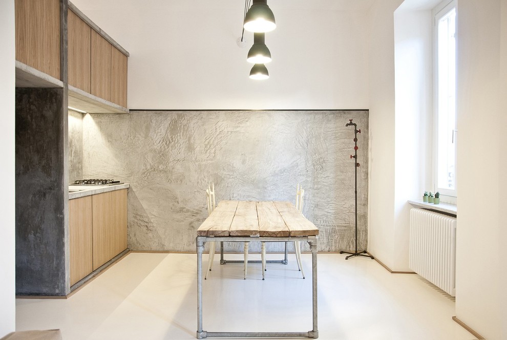 This is an example of a small industrial single-wall eat-in kitchen in Turin with a drop-in sink, flat-panel cabinets, medium wood cabinets, concrete benchtops, grey splashback and no island.