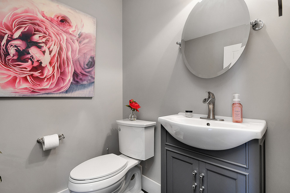 Inspiration for a small transitional dark wood floor and black floor bathroom remodel in Columbus with recessed-panel cabinets, gray cabinets, a two-piece toilet, gray walls, a vessel sink and white countertops