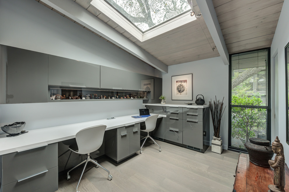 Design ideas for a mid-sized midcentury home office in San Francisco with grey walls, medium hardwood floors, a built-in desk and grey floor.