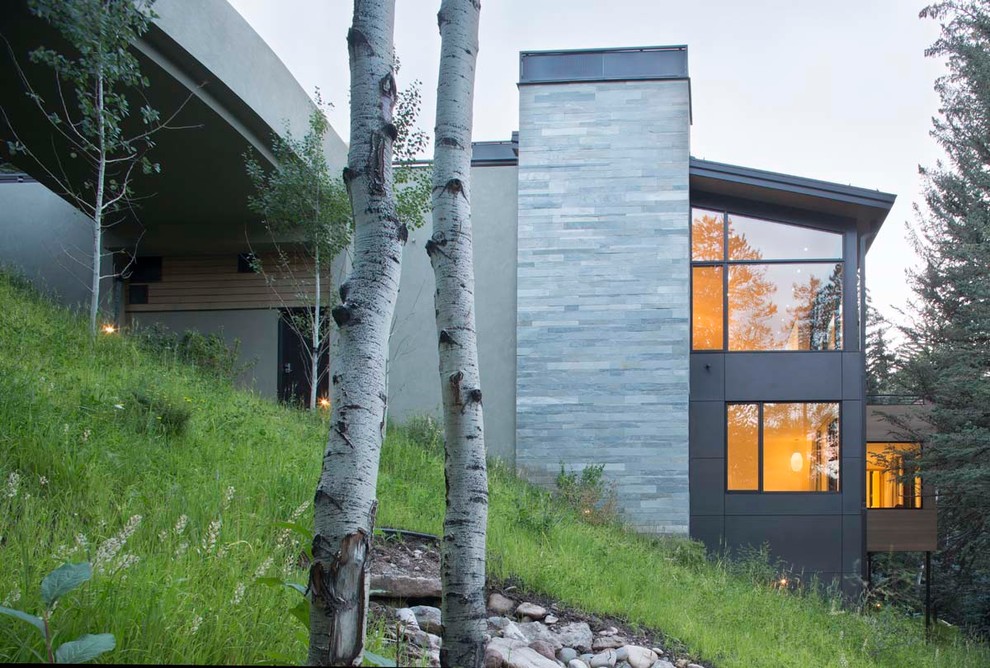 This is an example of a contemporary split-level grey exterior in Denver with mixed siding.
