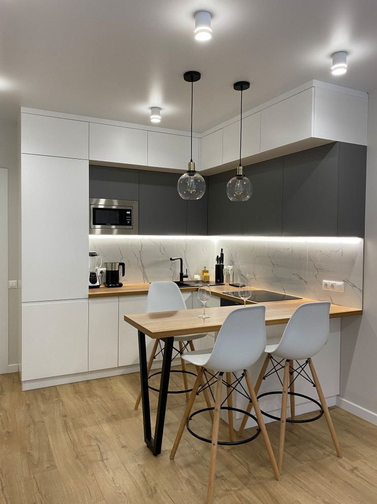 Photo of a mid-sized scandinavian l-shaped eat-in kitchen in Moscow with flat-panel cabinets, white cabinets, white splashback, with island, brown floor and brown benchtop.
