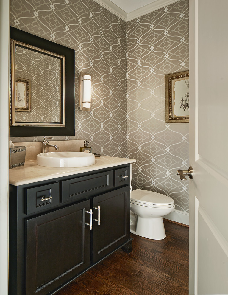 Design ideas for a traditional powder room in Dallas with recessed-panel cabinets, dark wood cabinets, ceramic tile, dark hardwood floors, marble benchtops, brown walls, a vessel sink, brown floor and beige benchtops.