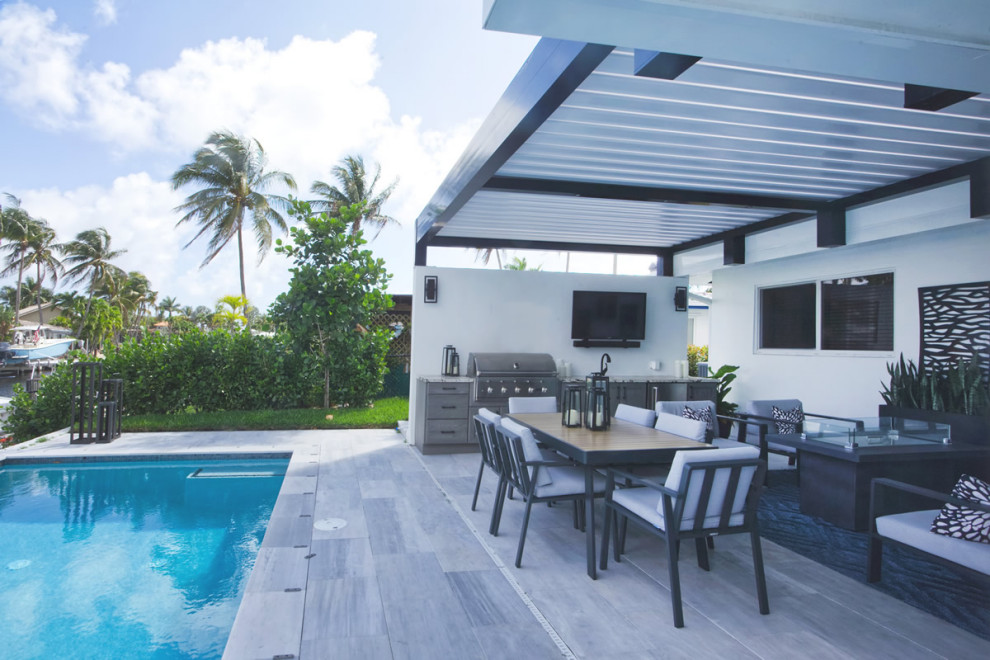 Photo of a medium sized coastal back patio in Miami with an outdoor kitchen, tiled flooring and a pergola.