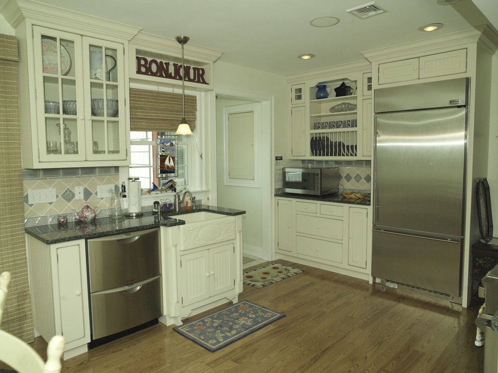 Photo of a small beach style u-shaped eat-in kitchen in Providence with a farmhouse sink, beaded inset cabinets, white cabinets, granite benchtops, blue splashback, ceramic splashback, stainless steel appliances, light hardwood floors, no island and brown floor.