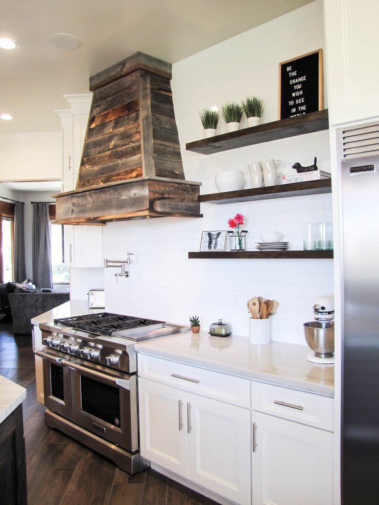 Large transitional porcelain tile and brown floor kitchen photo in Phoenix with white backsplash, subway tile backsplash, stainless steel appliances and an island