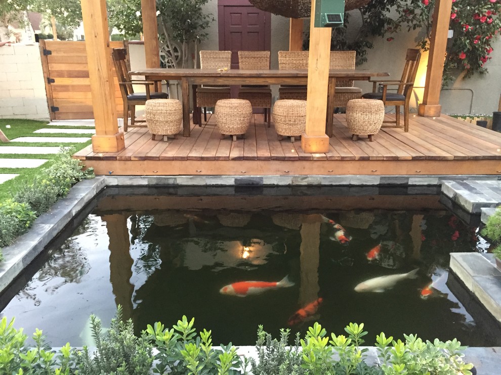 This is an example of a mid-sized modern backyard patio in Los Angeles with a water feature, decking and a pergola.
