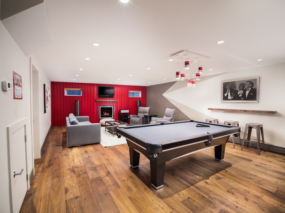 Inspiration for a mid-sized contemporary fully buried basement in Vancouver with a game room, grey walls, medium hardwood floors, a standard fireplace, a metal fireplace surround and brown floor.