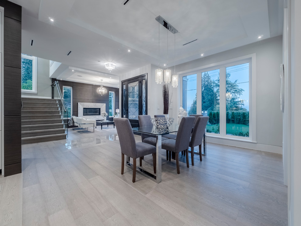 Large contemporary dining room in Vancouver with grey walls, light hardwood floors, no fireplace and grey floor.