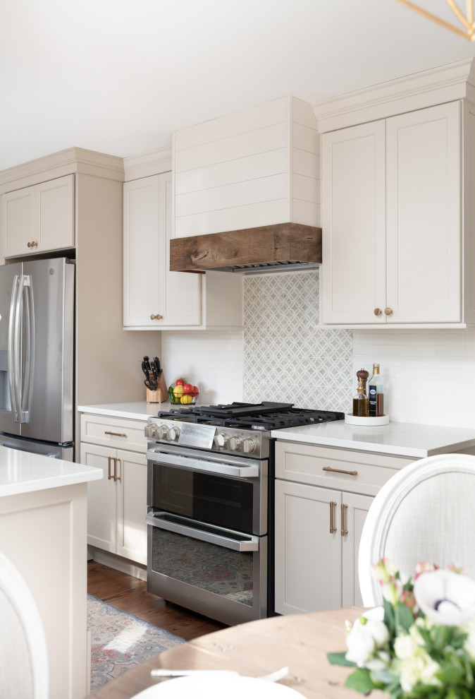 Inspiration for a small traditional galley kitchen/diner in Chicago with a belfast sink, flat-panel cabinets, white cabinets, engineered stone countertops, white splashback, ceramic splashback, stainless steel appliances, medium hardwood flooring, an island, brown floors and white worktops.