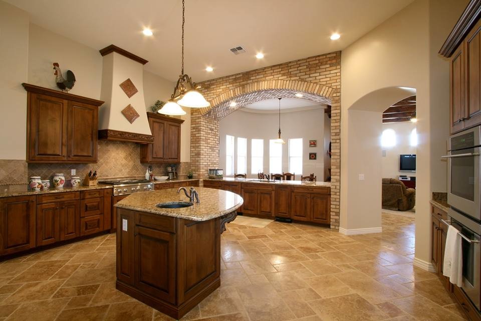Inspiration for a large l-shaped eat-in kitchen in Orange County with an undermount sink, raised-panel cabinets, dark wood cabinets, granite benchtops, brown splashback, ceramic splashback, stainless steel appliances, ceramic floors, with island and brown floor.