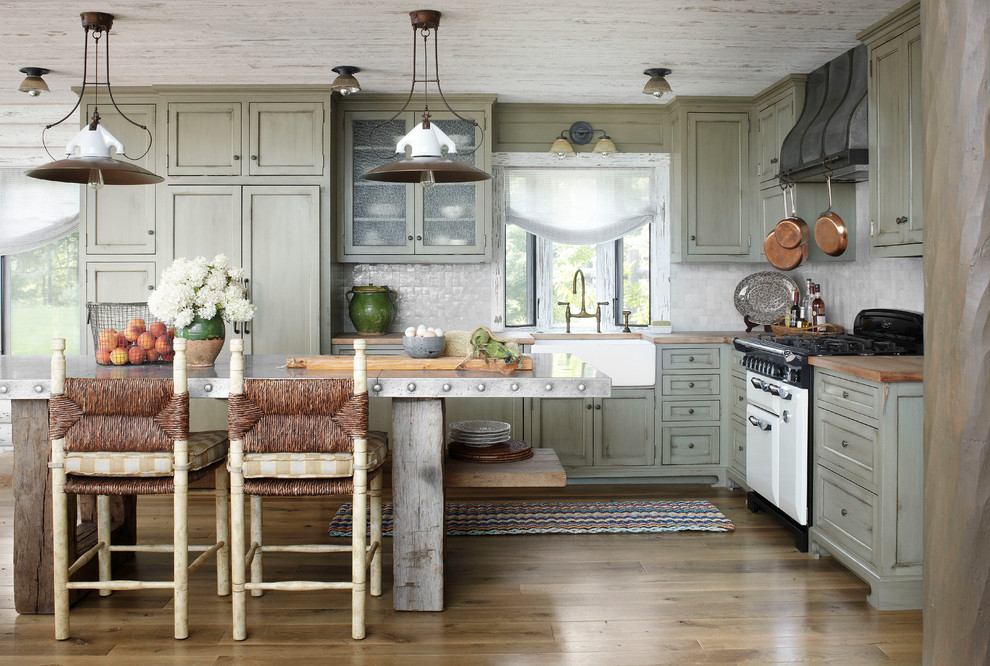 Inspiration for a country l-shaped kitchen in Milwaukee with a farmhouse sink, shaker cabinets, distressed cabinets, wood benchtops, grey splashback, mosaic tile splashback and panelled appliances.