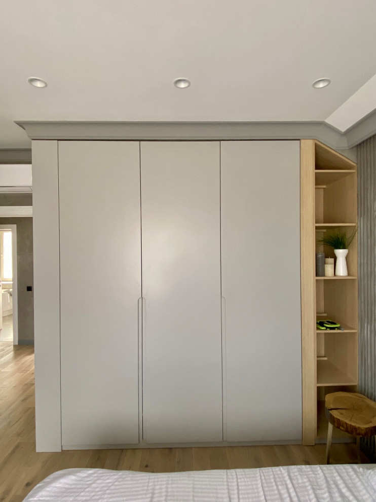 Photo of a medium sized contemporary gender neutral built-in wardrobe in Hertfordshire with flat-panel cabinets, grey cabinets, laminate floors, orange floors, exposed beams and feature lighting.