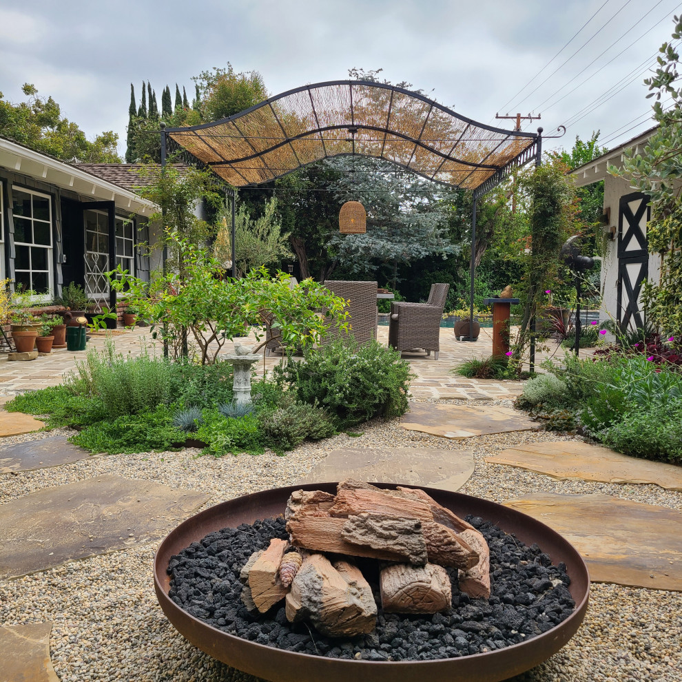 Photo of a rustic drought-tolerant backyard stone landscaping in Los Angeles with a pergola.