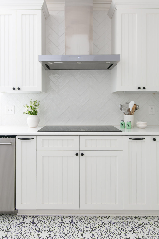 Large transitional porcelain tile and white floor open concept kitchen photo with a farmhouse sink, beaded inset cabinets, white cabinets, quartzite countertops, white backsplash, porcelain backsplash, stainless steel appliances and white countertops